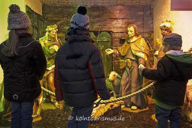 Children standing in front of a nativity scene at a Christmas market in Cologne Children standing in front of a nativity scene at a Christmas market in Cologne
